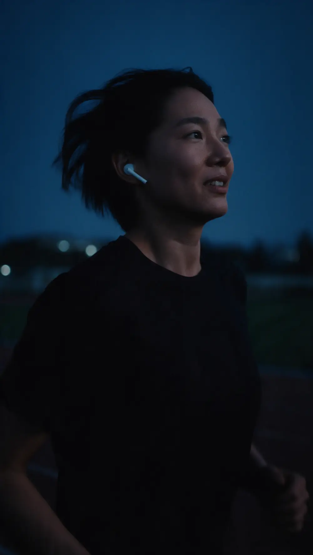 A runner with earbuds in, running at nightfall